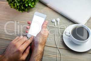 Person using smart next to coffee mug at desk