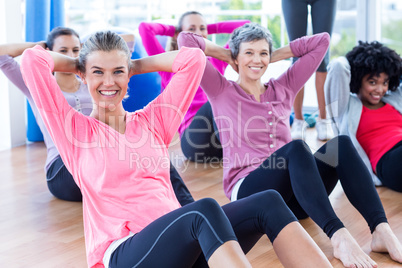 Cheerful women doing sit ups on hardwood floor