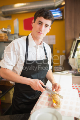 Portrait of male worker cutting sandwich