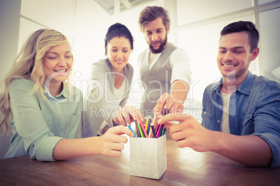 Smiling business people taking pencils