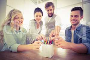 Smiling business people taking pencils