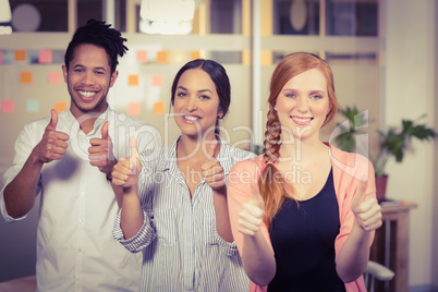 Business people showing thumbs up in office