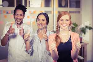 Business people showing thumbs up in office