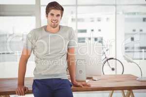 Hipster smiling while leaning at desk in office