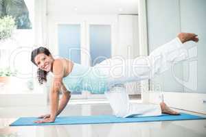 Smiling pregnant woman performing yoga on mat