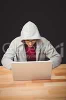 Man with hooded shirt working on laptop