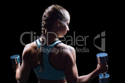 Rear view of woman exercising with dumbbells