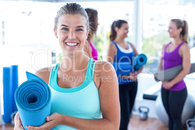 Portrait of cheerful woman with friends at fitness studio