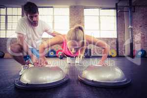 Male trainer assisting woman doing push ups