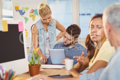 Businesswoman discussing with male colleagues using digital tabl