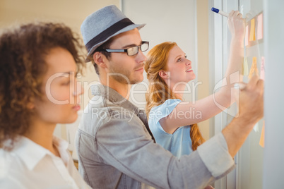 Business people writing on adhesive notes on glass wall