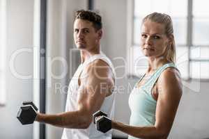 couple holding dumbbells looking at camera