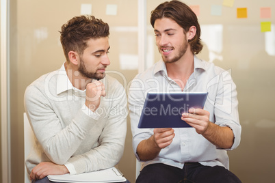 Businessman talking with male colleague using digital tablet