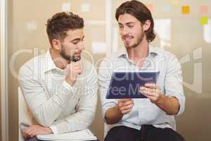 Businessman talking with male colleague using digital tablet