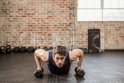 Man doing push up holding dumbbell