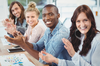 Portrait of smiling business people clapping at desk