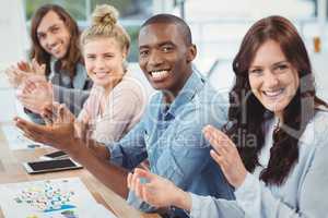 Portrait of smiling business people clapping at desk