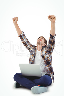 Hipster with laptop on lap cheering with arms raised