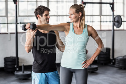 Male trainer helping woman with the dumbbells