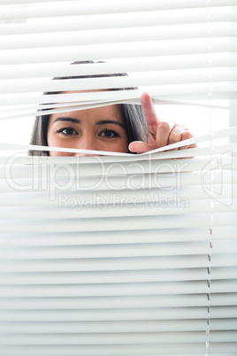 Woman peeking through some window blinds