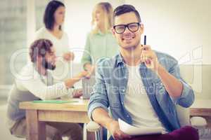 Portrait of smiling man showing pen at office