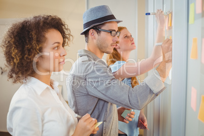 Business people writing on adhesive notes on glass wall