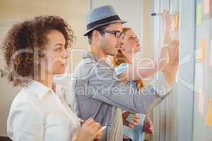 Business people writing on adhesive notes on glass wall