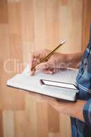 Cropped image of man writing on diary with pencil