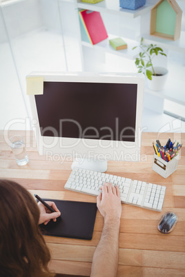 Hipster with graphics tablet working at computer desk