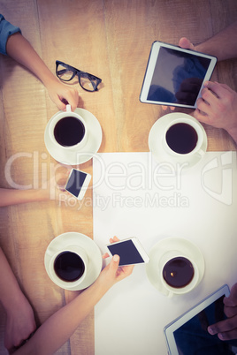 Overhead view of people using technology at desk