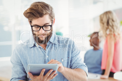 Man wearing eyeglasses using digital tablet at office