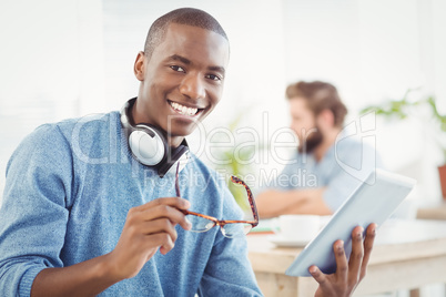 Portrait of smiling man with headphones while holding digital ta