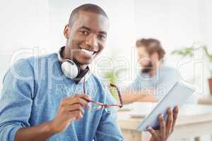 Portrait of smiling man with headphones while holding digital ta