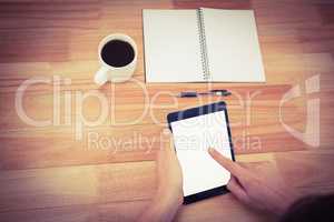 Hipster using digital tablet with book and coffee on table