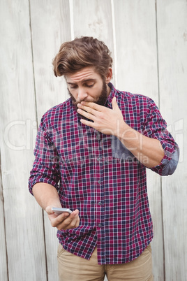 Shocked hipster looking at mobile