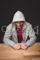 Man with hooded shirt sitting at desk in office