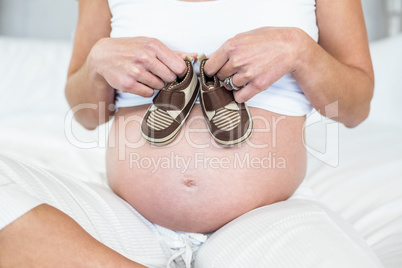 Midsection of woman with baby shoes on belly