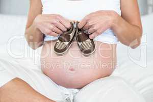 Midsection of woman with baby shoes on belly