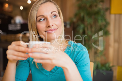 Thoughtful young woman holding coffee cup