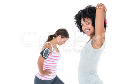 Woman stretching while female friend exercising