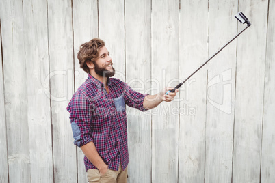 Happy hipster using selfie stick