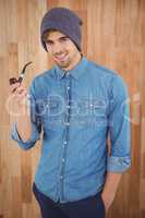 Portrait of hipster smiling while holding smoking pipe