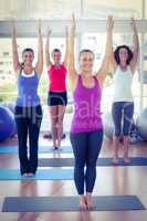 Cheerful women with arms raised in fitness studio