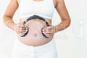 Pregnant woman holding headphones to belly