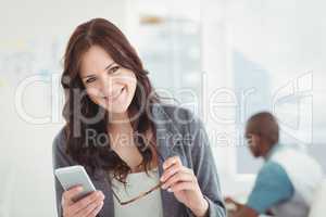 Portrait of happy businesswoman holding eyeglasses and smartphon