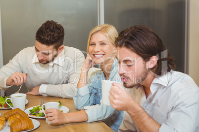 Businesswoman with male colleagues having snacks and coffee in c