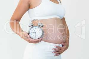 Pregnant woman showing clock and bump