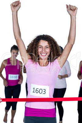 Portrait of smiling winner female athlete crossing finish line w