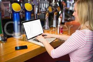 Woman working on laptop at bar counter