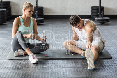 Sports couple stretching and drinking water